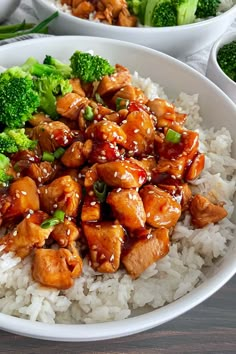 a white bowl filled with chicken and broccoli on top of rice covered in sauce