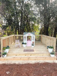 a wooden deck with potted plants on it and a pink door in the center