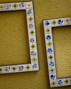 two white and yellow frames with flowers painted on the wall next to eachother