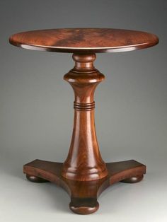 a wooden table with two pedestals on each side and one in the middle, against a gray background