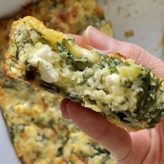 a hand holding up a piece of food with cheese and spinach on the side