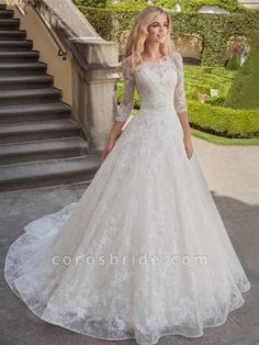 a woman in a white wedding dress standing on the steps near some bushes and stairs