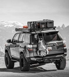 a black and white photo of a four door suv with luggage strapped to the roof