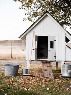 there is a chicken house that has been placed in the yard with two buckets next to it