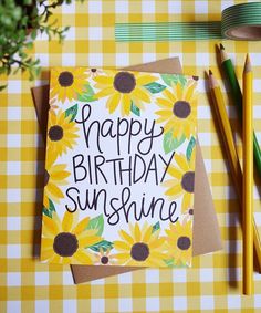 a happy birthday card with sunflowers on it next to pencils and paper