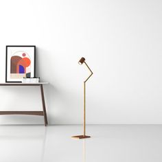 a floor lamp next to a table with a framed photograph on it and an art piece