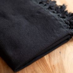 a black cloth is laying on a wooden table with some sort of material in the background