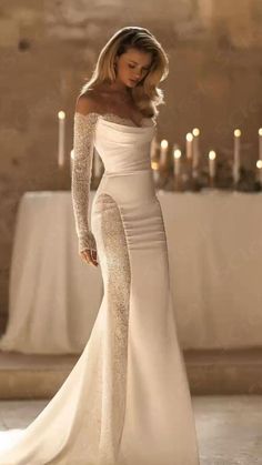 a woman in a white dress standing next to candles