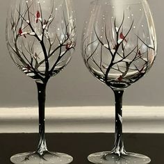 two wine glasses with branches painted on them