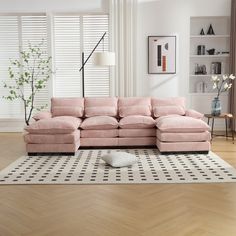 a living room with a large pink couch and white rugs on the wooden floor