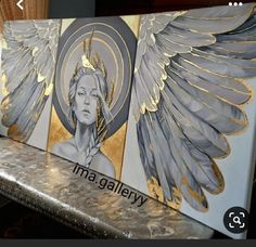 an art piece with gold and silver wings painted on it's side, sitting on a marble bench