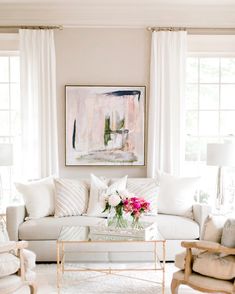 a living room filled with lots of white furniture and decor on top of a rug