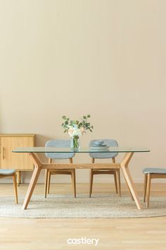 a glass table with two chairs and a vase filled with flowers