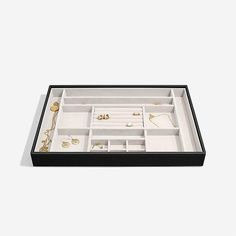 a black and white box with jewelry in it's compartments on a white background