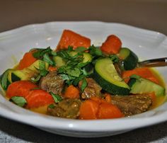 a white bowl filled with meat and veggies on top of a marble table