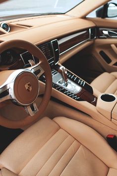 the interior of a luxury car with beige leather and tan stitching on the steering wheel