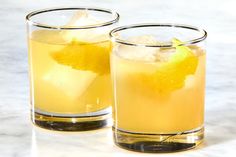 two glasses filled with lemonade sitting on top of a counter next to each other