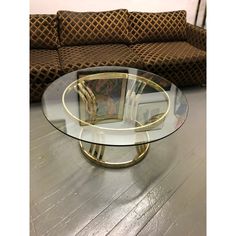 a glass and brass coffee table in the shape of a flower vase on a wooden floor