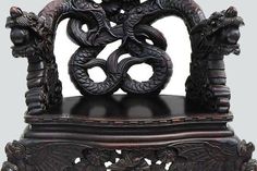 an intricately carved wooden chair with two snakes on it's back and sides