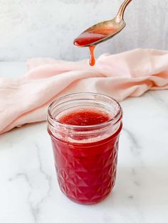 a spoon pouring ketchup into a jar