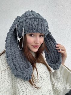 a woman wearing a gray knitted hat and scarf with pearls on the ear,