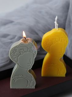 a candle that is sitting next to a small figurine on a table in front of a bed