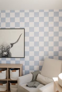 a living room with blue and white checkered wallpaper, a cow painting on the wall