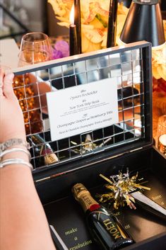 a person holding a wine bottle in front of a table with candles and other items