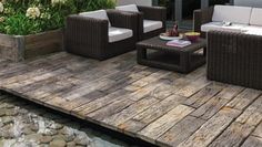 two wicker chairs sitting on top of a wooden deck next to a small pond