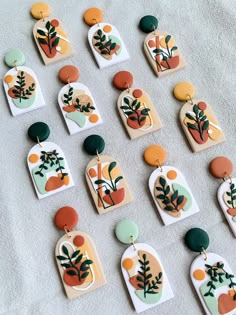 many different shapes and sizes of earrings on a white tablecloth with grey linen behind them