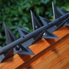 three metal spikes on top of a wooden fence