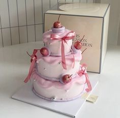 a three tiered cake sitting on top of a white table next to a box