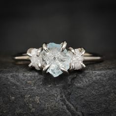 a white diamond ring sitting on top of a rock