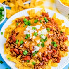 a white plate topped with nachos covered in chili and cheese