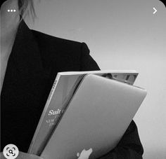 a woman holding an apple laptop computer in her hands and looking at the screen while wearing a suit