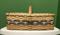 a wicker basket sitting on top of a white toilet next to a green wall