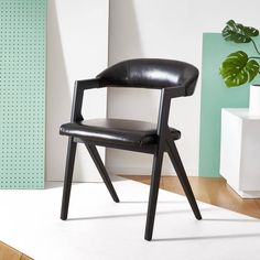 a black leather chair sitting on top of a white floor next to a potted plant