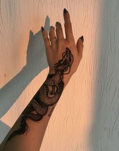 a woman's arm with a tattoo on it and her hand in the shape of a dragon