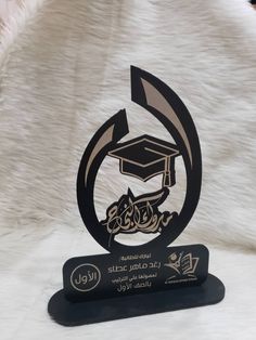 a black and gold trophy with a graduation cap on it's head in arabic writing