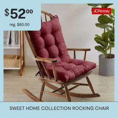 a red rocking chair sitting on top of a wooden floor next to a potted plant