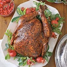 a roasted turkey on a platter with tomatoes and herbs