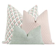 three pillows with different patterns on them, one pink and the other light green are sitting next to each other