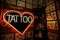 a tattoo shop with lots of pictures on the wall and neon sign in the shape of a heart