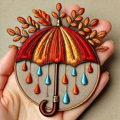 a hand holding an embroidered umbrella with raindrops on it