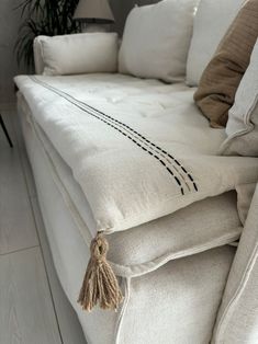 a close up of a couch with some pillows on it and a plant in the background