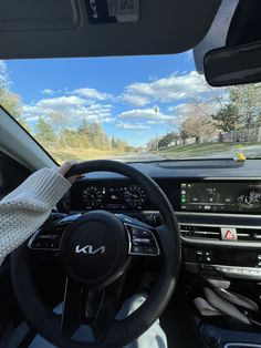 the driver's hand on the steering wheel of a car driving down a road