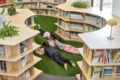 two people laying on the ground in a library with bookshelves and artificial grass