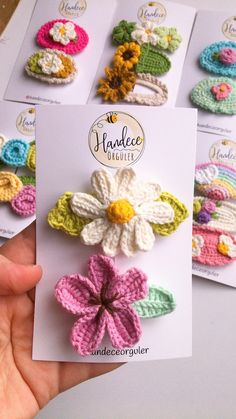 crocheted flower broochies are displayed in front of a card for purchase