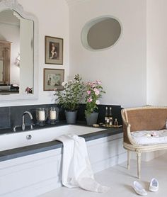 a bathroom with a sink, mirror and flowers on the counter top in front of it