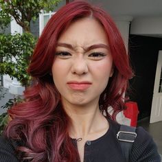 a woman with red hair is making a funny face